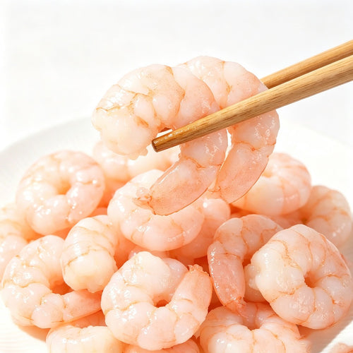 Pile of peeled shrimp meat on a white plate with chopsticks lifting one piece