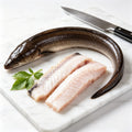 Raw eel and two eel fillet portions on a marble board with a kitchen knife